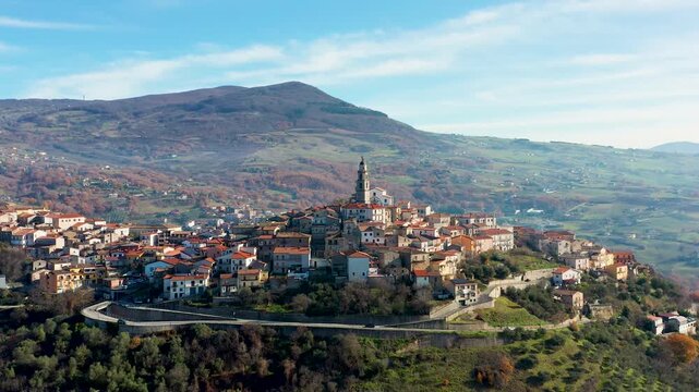 Aerial view of the clustered buildings and prominent church tower of Picerno village, perched atop a hill with winding roads, Picerno, Basilicata, Italy.