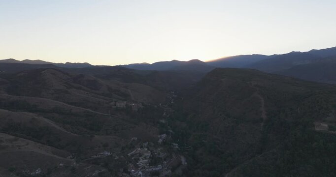 Drone aerial over Granada foothills at sunrise, rolling ridges and soft dawn gradients framing the city near the Alhambra, Andalusia Spain