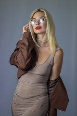 Fototapeta premium Fashion portrait of blonde woman adjusting glasses in studio