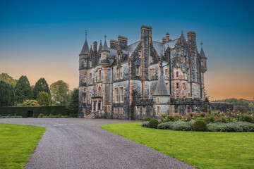 The exterior of Blarney house, built in a Scottish baronial style, in Cork, Ireland, captured in autumn under a moody sunset sky