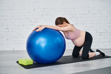 Obraz premium Empowered pregnant woman practicing prenatal fitness with a stability ball in a serene space