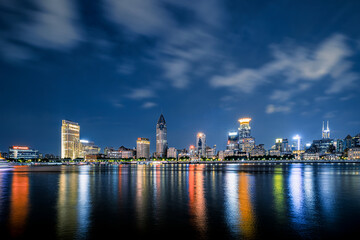 Obraz premium Vibrant illuminated skyline of the Bund at night in Shanghai, China with colorful reflections on the Huangpu River.