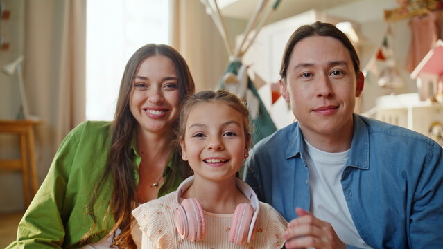 Mom dad kid looking camera smiling at cozy apartment closeup. Portrait family