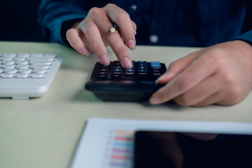 Close up business finance work with hands using calculator and pencil on desk. Accounting calculation, budgeting process, financial analysis, data review and professional office workflow.