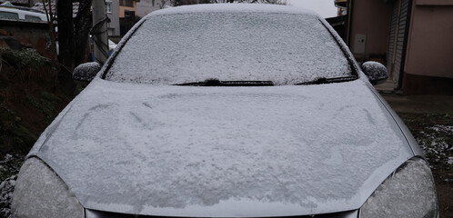Frozen winter car covered snow at street, view front window windshield hood on snowy background window texture freezing ice glass background Front view