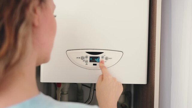 silhouette woman turning down heating to minimum in order to save on utility bills. boiler appliance, person hand finger pressing button control dial digital thermostat display to lowers temperature