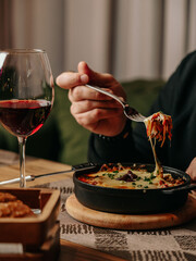 Cheesy baked pasta being lifted with fork in cozy restaurant setting
