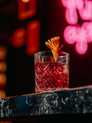 Negroni cocktail in crystal rocks glass with orange peel on marble bar