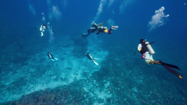 Underwater shot following a group of SCUBA Divers as they descend towards a coral reef