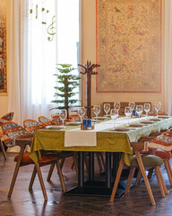 Elegant formal dining room with table set for ten, decorative tapestry, chandelier, and polished wood floor
