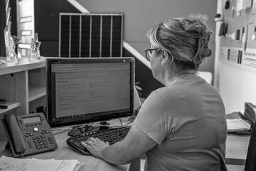 Happy office assistant typing on a keyboard while managing tasks and documents in a bright workspace