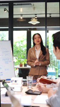 Young business woman executive ceo leader discussing project management planning strategy working with diverse colleagues company team at office corporate board group meeting.