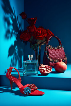 Bodeg&oacute;n de moda y belleza: sandalia roja, bolso bordado y perfume sobre fondo azul, Mockup para campa&ntilde;a de perfume femenino, Banner para San Valent&iacute;n o D&iacute;a de la Madre
