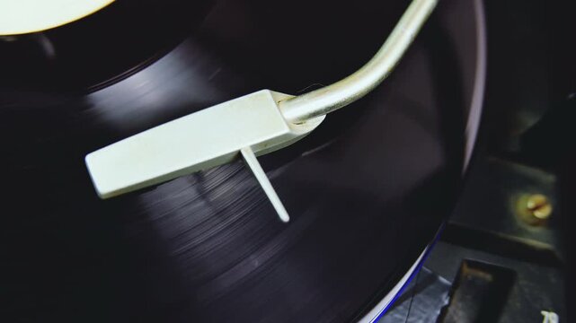 Vintage turntable hi-fi system playing a vinyl record. Shot from a motorized slider moving left. Music album LP spinning with the needle cartridge.
