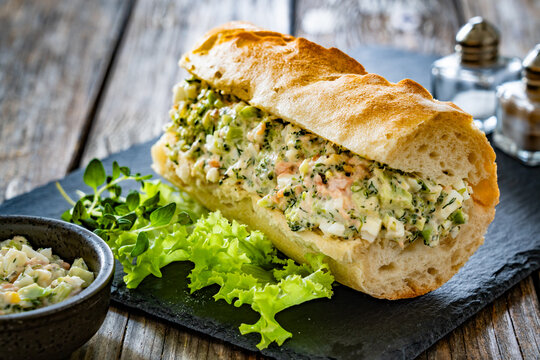 Crispy baguette with egg salmon avocado paste on wooden table