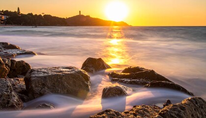 Obraz premium Golden hour at the beach with rocks and blurred waves.