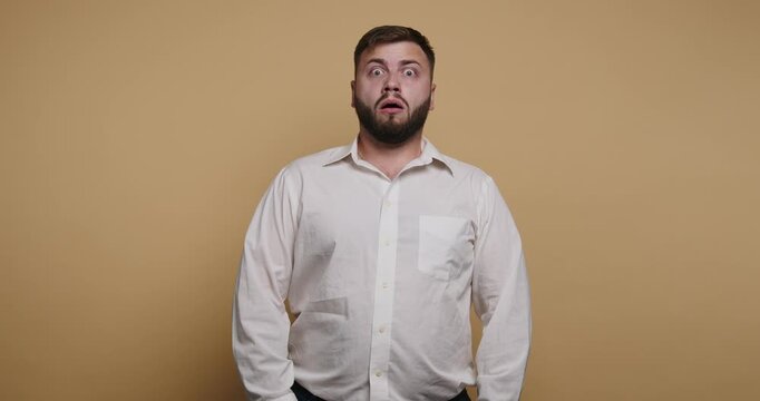 Man shows surprise in a studio setting with a plain background and simple lighting during a photo shoot