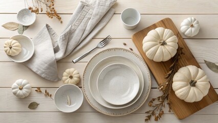 High-angle view of a modern minimalist Thanksgiving table with white ceramics and neutral autumn decor on light wood.