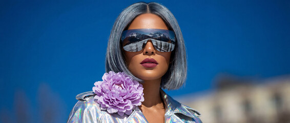 Stylish woman with sunglasses and flower accessory under blue sky, fashion statement