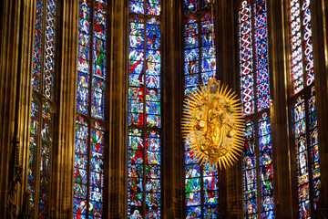 Interior of historic cathedral with golden Madonna sculpture and colorful stained glass windows. Religious art and gothic architecture background for travel, culture and spirituality themes. © Инна Мадеева