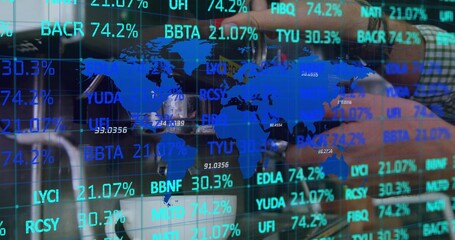 Displaying blue world map and tickers on glass in office, forearm in green plaid shirt reaching