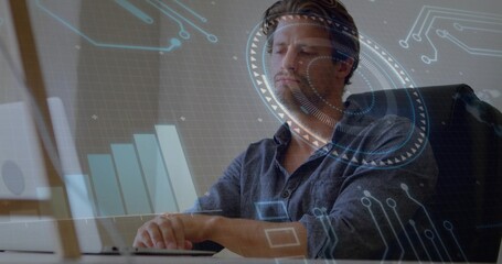 Analyzing data, adult man wearing dark button-up shirt working at office desk with laptop and HUD