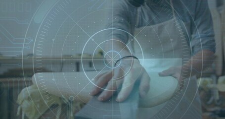 Shaping artisan in shirt with rolled sleeves holding round object in maker studio, with HUD overlay