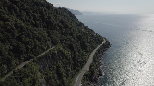 Aerial view of the Kvariati coastline in Adjara, Georgia, featuring a seaside highway beneath green mountain slopes along the Black Sea near the Turkish border.