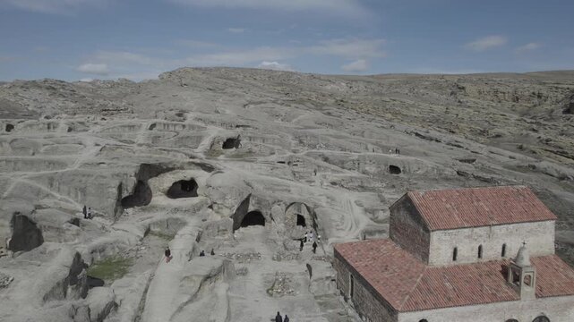 Aerial drone view of the Uplistsuli Church of the Prince in Uplistsikhe, Georgia, captured from a moderate height, revealing rock-hewn stone architecture within the ancient cave town near Gori.