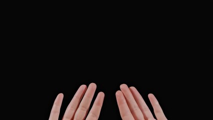 Hands raising in darkness: gesture of hope and expression on a black background
