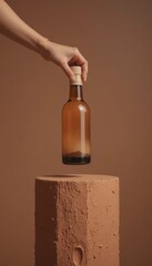 Female hand holds a brown glass bottle containing dark grains topped with a wooden cap above a rustic terracotta