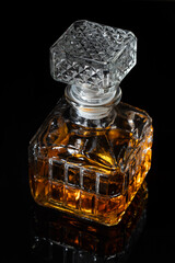 Glass carved decanter with brandy on a black table