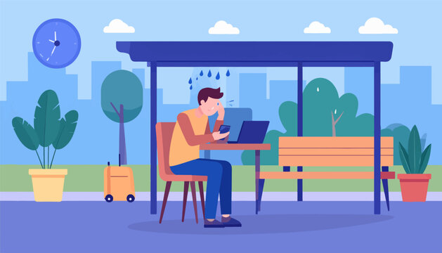 Man on phone and laptop at covered bus stop during rain