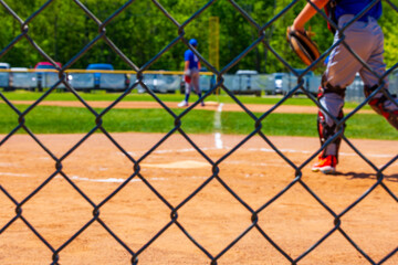 Selective focus on a chain link fence at a youth baseball game blurred in the background.