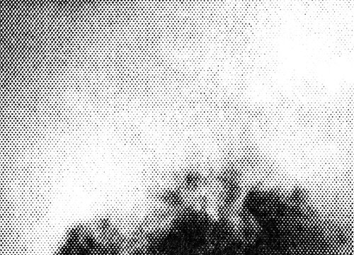 Extreme macro of black printer halftone dots forming soft clouds and sky gradient above a dark horizon silhouette, isolated on a transparent background