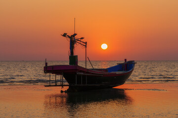 Fototapeta premium Fishing boats on the beach when the sun begins to set with a beautiful backdrop of sea and sand.