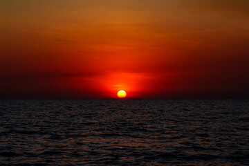 Beautiful sunset landscape with clouds floating above the sea waves.