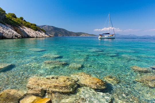 Distant view of a sailboat anchored in the Ionian Sea by a beach, Ithaki, Greece