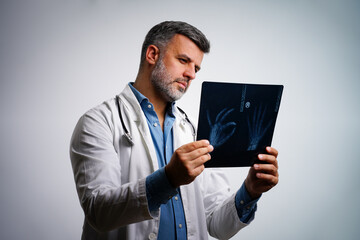 Male doctor examining hand x-ray scan with copy space in clinic