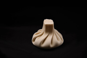 One handmade khinkali on a black background