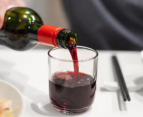 Closeup shot of red wine bottle pouring wine into glass