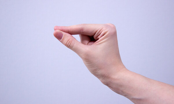 hand showing gesture meaning 'a little' , 'small' or 'tiny' , isolated on light-blue background