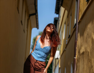 Obraz premium Young caucasian female joyfully posing in narrow alley on sunny day