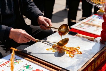 Artisan creating traditional sugar painting using a ladle and molten sugar on a metal surface