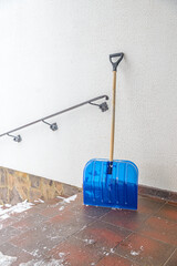 A large shovel for clearing snow from the porch of a residential building in winter