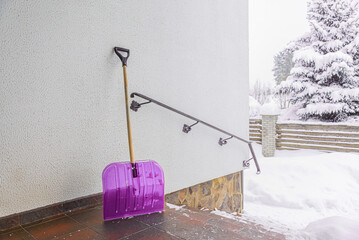 A large shovel for clearing snow from the porch of a residential building in winter