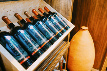 Obraz premium 7 November 2025, Tbilisi Airport, Georgia: wine bottles on wooden shelves next to a traditional qvevri