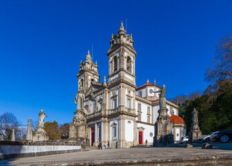 Obraz premium A grand, ornate stone church with twin bell towers stands majestically under a clear blue sky