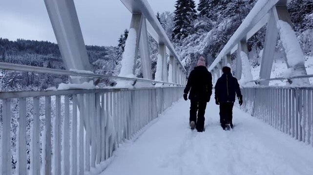 Enfants marchant sur un pont enneig&eacute; en hiver, video 4k drone