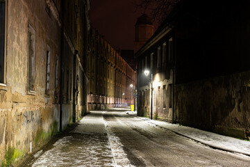 Obraz premium Ulica Gimnazjalna w mieście Zagan w zachodniej Polsce. Z lewej strony, na całej długości ulicy znajduje się budynek po kolegium jezuickim. Jest zimowa noc.